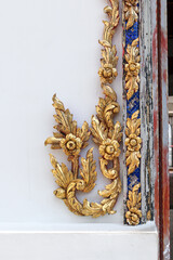 Golden low-relief decoration on a frame. A beutiful low relief sculpture depicting image of flowers decorated on window and frame inside Wat Pho.