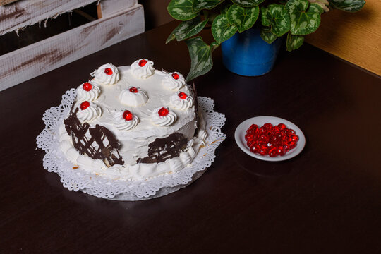 Pastel de crema y chocolate cn guindas, adornado con planta y plato de guindas