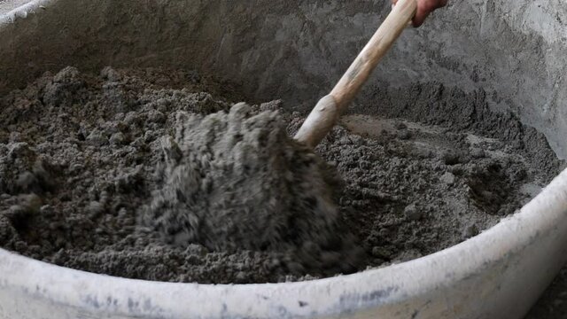 Putting concrete from basin to bucket closeup