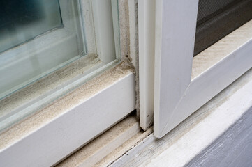 dirty dust piled up in plastic window frames.