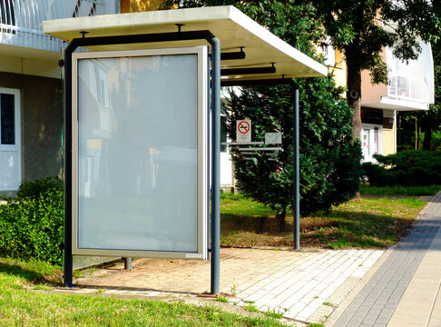 bus shelter at bus stop. white poster ad display. background for mock-up. advertising concept. composite image. blank white glass & metal structure. clear glass design. urban setting. green background