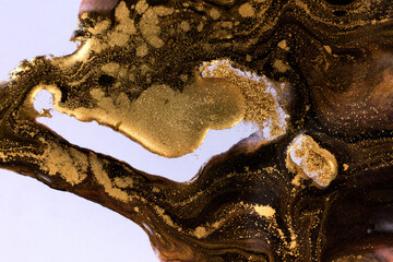 Black and gold mixed inks splattered on white paper background.