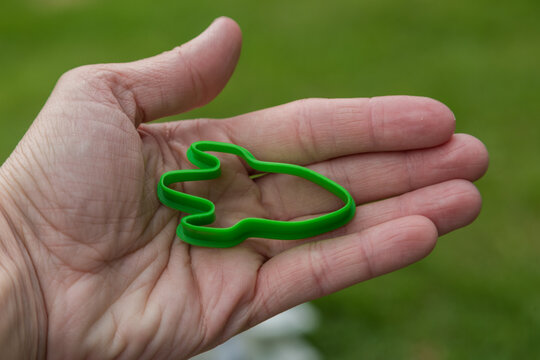The hand of an adult holds a cookie mold or a toy mold in the form of a rocket.