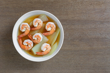 top view of hot and sour soup with shrimp and green papaya in a ceramic bowl on wooden table, copy space. asian homemade style food concept.
