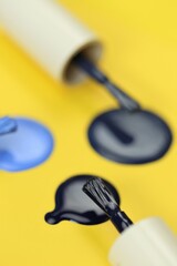 Blue nail polish set on a bright yellow background.Drops of nail polish blue shades and brush .Beauty and fashion concept.Hand and Nail Care