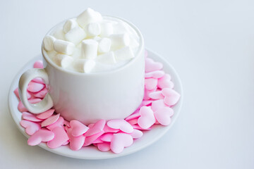 Cappuccino cup decorated with pink hearts and marshmallows on white background