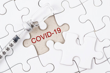 Vaccine and syringe injection with COVID-19 text on jigsaw.