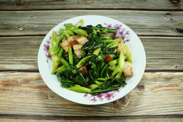 Fresh Chinese kale with roasted crispy pork and seasoning with pepper and fish sauce on the plate. Famous ancient food in Asia restaurant. Appetizer menu and side dish with porridge rice.  