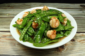 Fried fresh peas and peeled shrimp seasoning with soy sauce and pepper on the plate. Famous luxury appetizer menu in Asia restaurant. 
