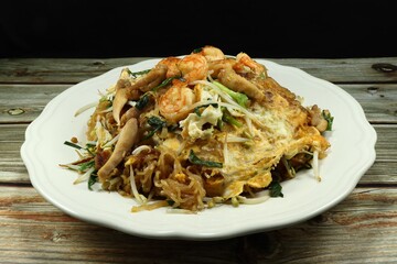 Famous fried noodle (Pad thai) with sprouts, egg, and fresh peeled shrimp on the plate. Popular traditional Thai food in Asia. 