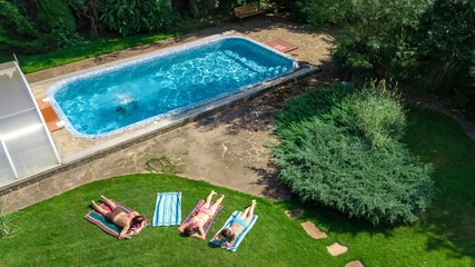 Happy family relaxing by swimming pool, aerial drone view from above of parents and kids have fun on vacation, family weekend on resort
