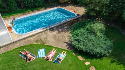Happy family relaxing by swimming pool, aerial drone view from above of parents and kids have fun on vacation, family weekend on resort
