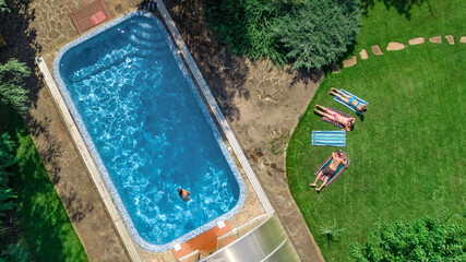 Happy family relaxing by swimming pool, aerial drone view from above of parents and kids have fun on vacation, family weekend on resort
