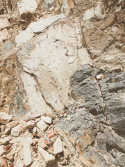 Natural background. Closeup edged shabby cliff cracks. Gray-brown stone rock texture of mountains. Vintage and faded matt style colour in tinted photo. Concept of geolog, mountaineering or hard work