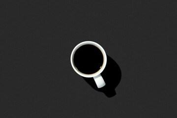 White cup with a coffee on a black background. Top view, flat lay