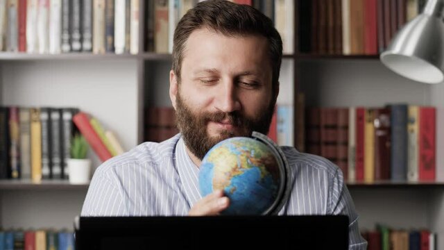 Dreams of vacation. Male office worker at workplace looks at globe map of world and dreams of weekend or vacation. vacation planning, vacation, travel, route concepts. Close-up