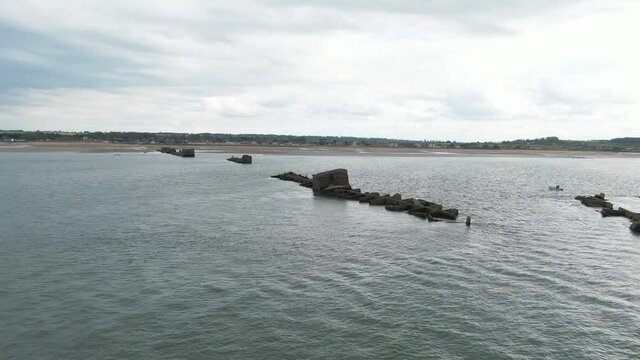 WWII ruins of concrete bunkers surrounded by shallow lagoon on Mulberry beach in Normandy, France