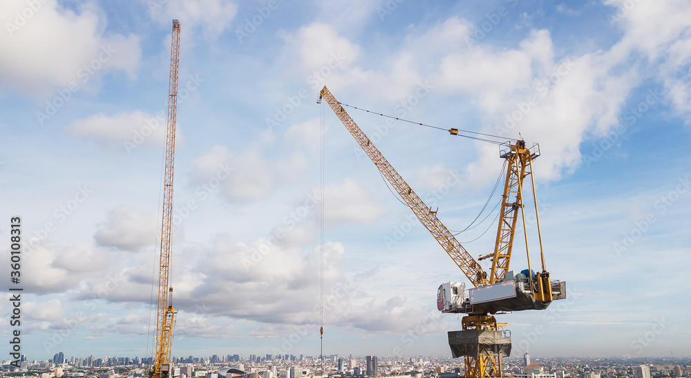 Wall mural large construction site including several cranes working on a building complex, with clear blue sky 