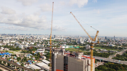 Fototapeta na wymiar Large construction site including several cranes working on a building complex, with clear blue sky and the sun
