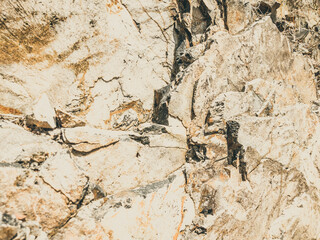 Natural background. Closeup edged shabby cliff cracks. Gray-brown stone rock texture of mountains. Vintage and faded matt style colour in tinted photo. Concept of geolog, mountaineering or hard work