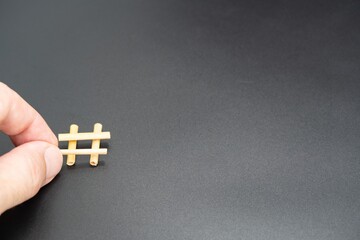 The hashtag sign, a symbol of social networks, is laid out from scraps of straw. Fingers hold one of the scraps of straw.