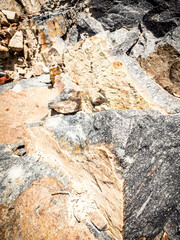 Natural background. Closeup edged shabby cliff cracks. Gray-brown stone rock texture of mountains. Vintage and faded matt style colour in tinted photo. Concept of geolog, mountaineering or hard work