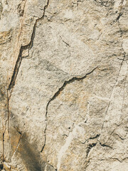 Natural background. Closeup edged shabby cliff cracks. Gray-brown stone rock texture of mountains. Vintage and faded matt style colour in tinted photo. Concept of geolog, mountaineering or hard work