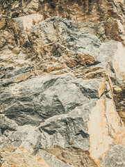 Natural background. Closeup edged shabby cliff cracks. Gray-brown stone rock texture of mountains. Vintage and faded matt style colour in tinted photo. Concept of geolog, mountaineering or hard work