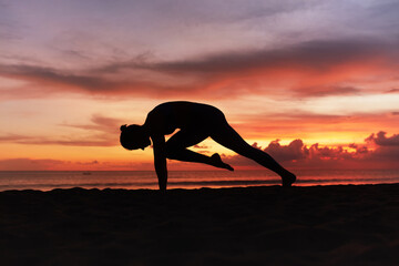 Yoga Poses. Woman Practicing Cat Stretch Asana On Ocean Beach. Female Silhouette Standing In Marjariasana Pose At Beautiful Sunset. Yoga As Exercise For Lifestyle.
