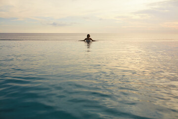 Ocean. Woman Standing In Sea. Girl Touching Water Surface And Looking Away. Beautiful Seascape And Female Silhouette. Vacation In Tropical Country.