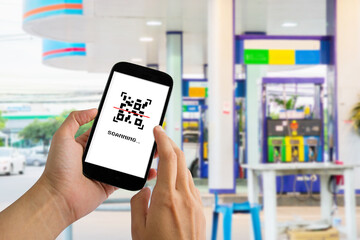 Man use smartphone scanning QR code for make a payment for refueling car on gas station