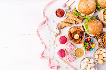 Unhealthy food. Sweets and fast food top view flat lay with a measure tape