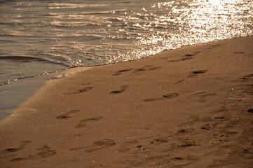 Sea waves and footprints on a sandy beach. Nature background.