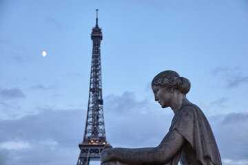 Fototapeta na wymiar Eiffel Tower in Paris at evening with sculpture of a woman and the moon