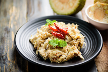 Northern Thai food (Tam Khanun), spicy pounded young jackfruit salad on black plate, Local Thai food	