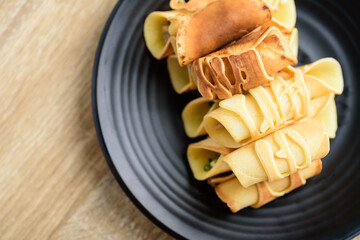 Thai dessert (Khanom Tokyo), pancake roll stuff with minced pork on black plate	