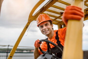 young man contractor in overalls and orange protective helmet drive a construction loader machine © Med Photo Studio