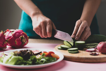 Obraz na płótnie Canvas Woman cutting vegetables preparing for making vegan salad