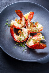 Traditional barbecue spiny lobster tail sliced and offered with lemon slice and herbs as closeup on...