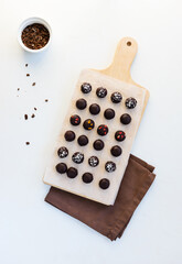 Homemade sweets made from oatmeal, walnuts and raisins, coated with dark chocolate, sublimated berries and coconut flakes on a wooden board. Sugar free, gluten, lactose. 