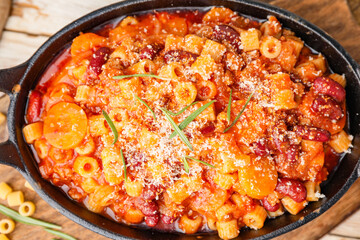 Dish with tasty pasta and beans on table, top view