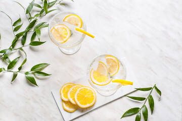 Glasses of tasty martini cocktail with lemon on light background