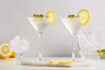 Glasses of tasty martini cocktail with olives on light background