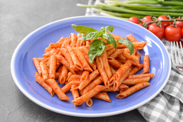 Plate with tasty pasta and tomato sauce on dark background