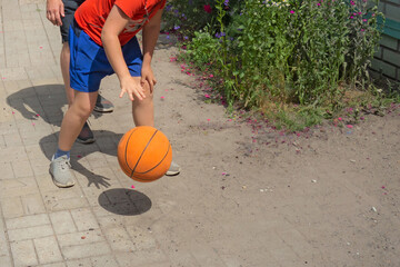Teenager plays basketball with his father. Closeup view with no faces. Boy and man bounce the ball on a backyard. Sport fans at sunny summer day