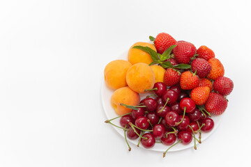 Assorted fruits in white bowl isolated on white background. Bowl of healthy fresh fruit. Top view. Strawberry, cherry, apricot. High quality photo