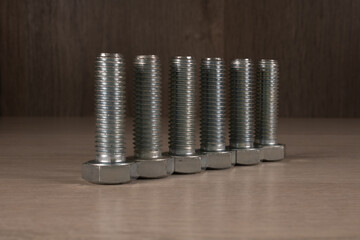 Galvanized steel hex bolts on dark wood background.