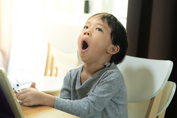 A kid is bored with study online, he wants to play an airplane toy.