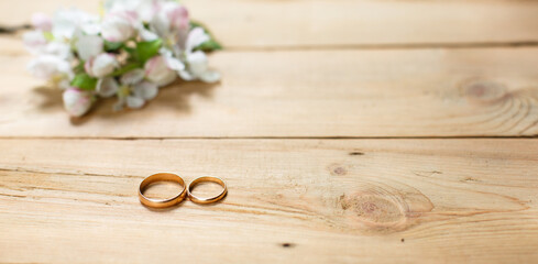 Obraz na płótnie Canvas Two gold rings on a wooden background with white Apple blossoms. Wedding in eco-style, rustic. Couple in love, ceremony and registration, details, bride's fees, groom's morning. Space for text. flatly