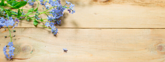 Naklejka premium Blue small forget-me-nots flowers on a wooden background. The concept of eco style, natural texture. Space for text. Flatlay